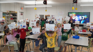  students holding up pictures of the shoes they drew